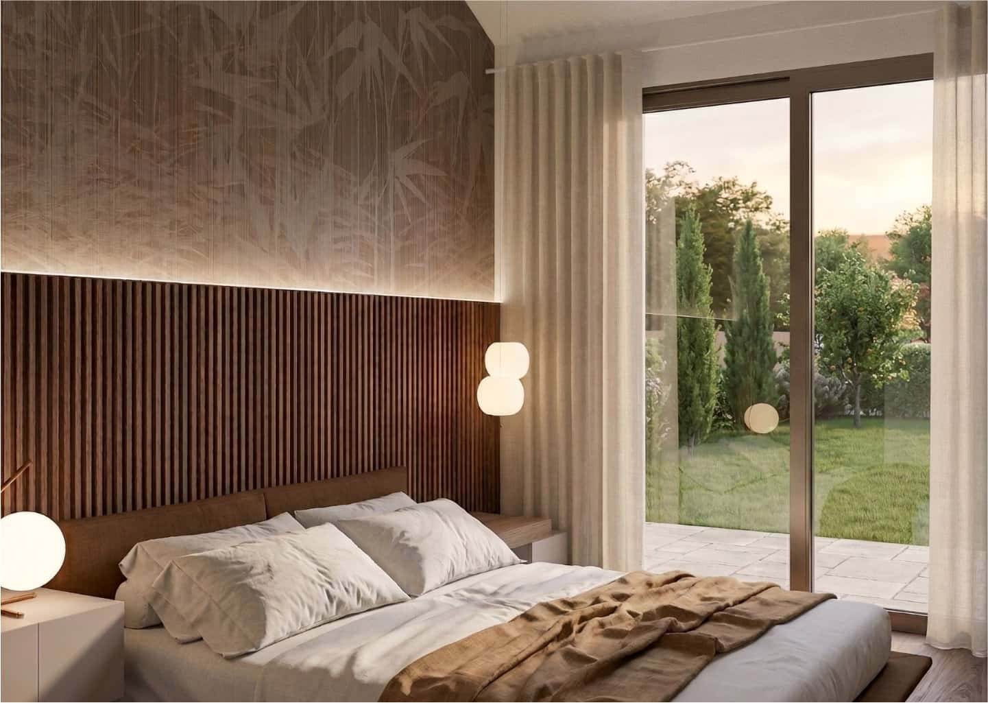 A cozy bedroom with wooden panel accents, a neatly made bed, soft lighting, and large glass doors overlooking a lush garden with trees.